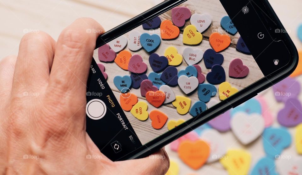 Taking photos to sell online with phone, woman’s hand holding phone and focusing, hearts scene shot digitally to sell online, photography sold online, Foap app sales, selling photos with a smartphone 