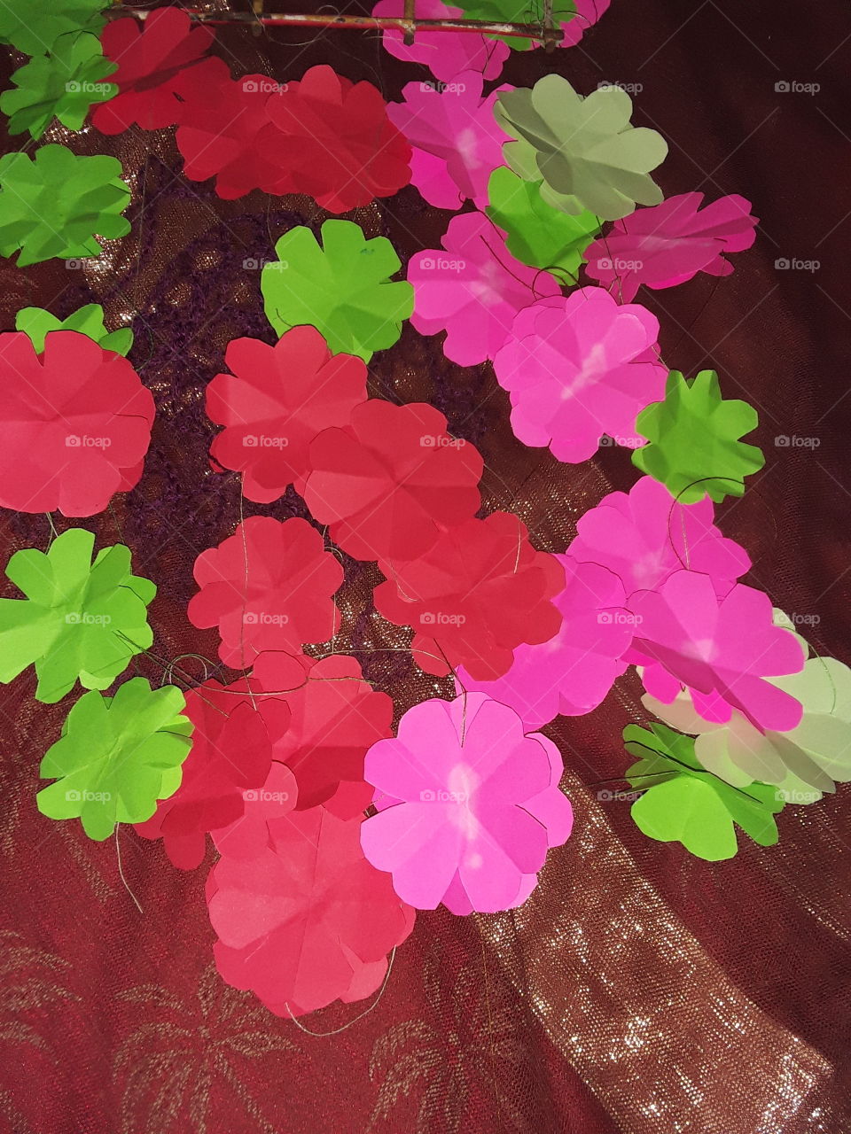 this is picture of red pink green colour flowers and background is broun colour cloth. it is very colourful picture.