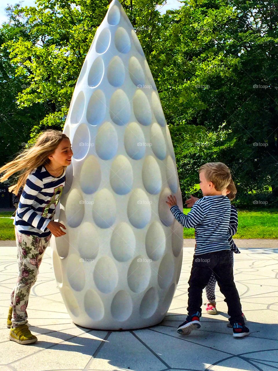 Children playing near the white statue