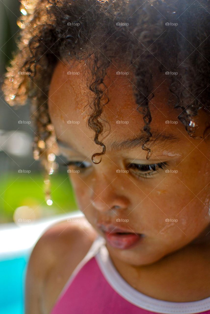 Cute little girl enjoying some playtime in a swimming pool during a hot summer day, looking for refreshment - portrait beauty