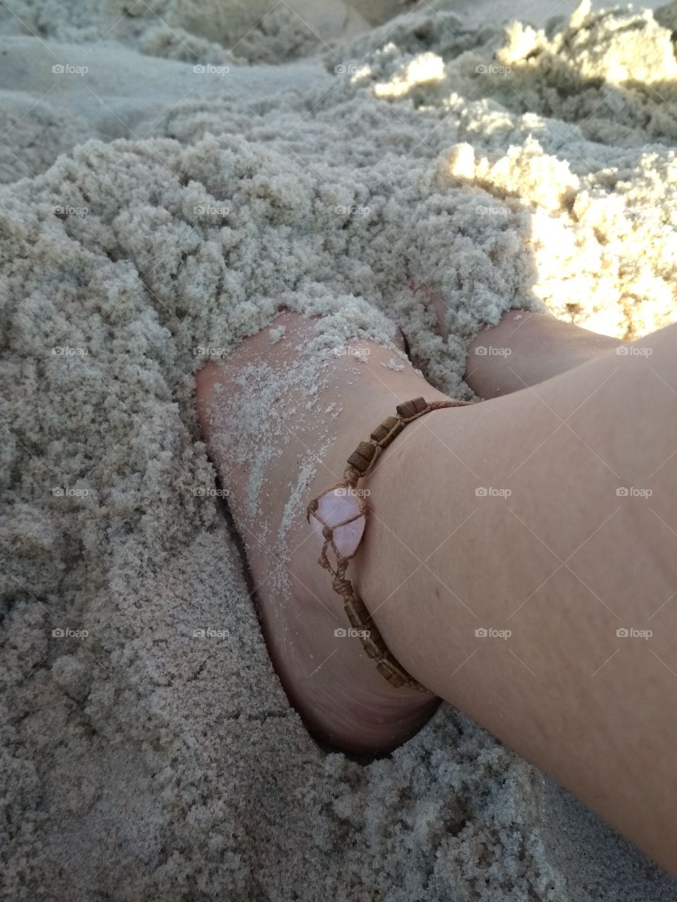 pés descalços na areia usando quartzo Rosa
