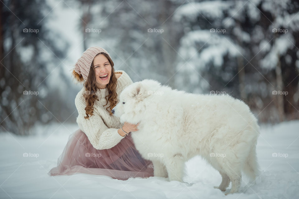 Beautiful woman with dog samoyed in winter forest