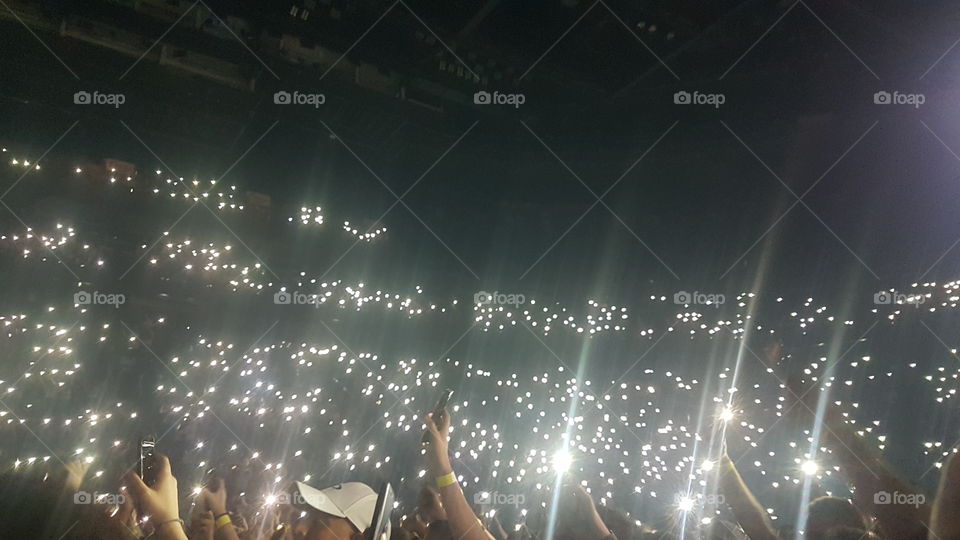 Auditorium illuminated by people's cellphone lamp like stars in the dark. Centre Bell, Montréal, Québec, Canada.