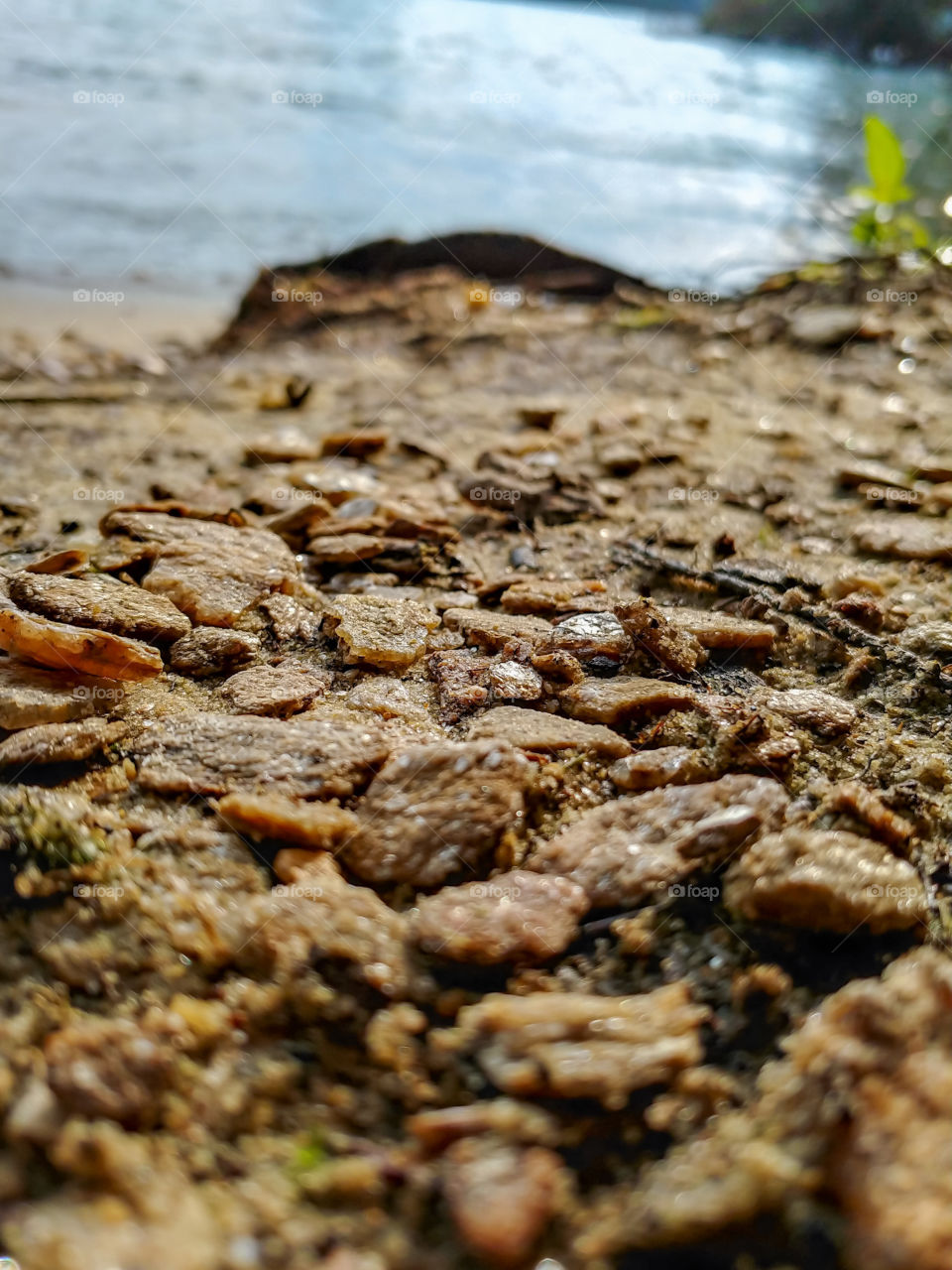 Rocks Pebbles and sand with water in background.