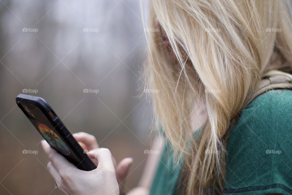 Woman with Blonde hair on phone wile outdoors