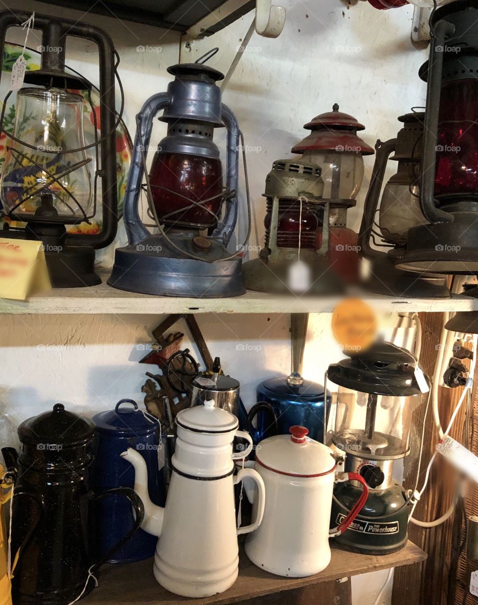 Old antique lanterns on a shelf and old teapots in an antique shop. 