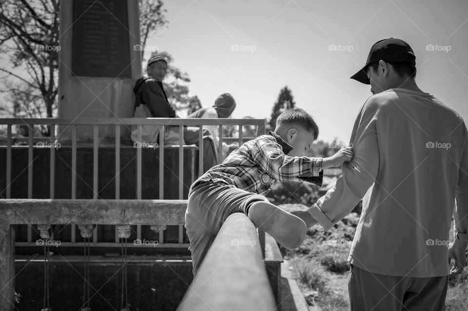 A small boy attempts to cross a railling