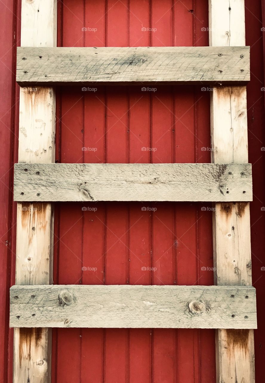 Rustic wooden ladder against a bright red wall