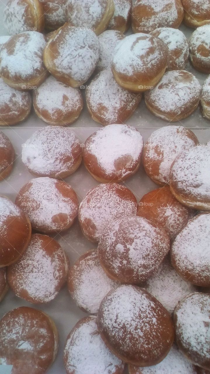 Many delicious sweet doughnuts with powder
sugar on for sale in bakery