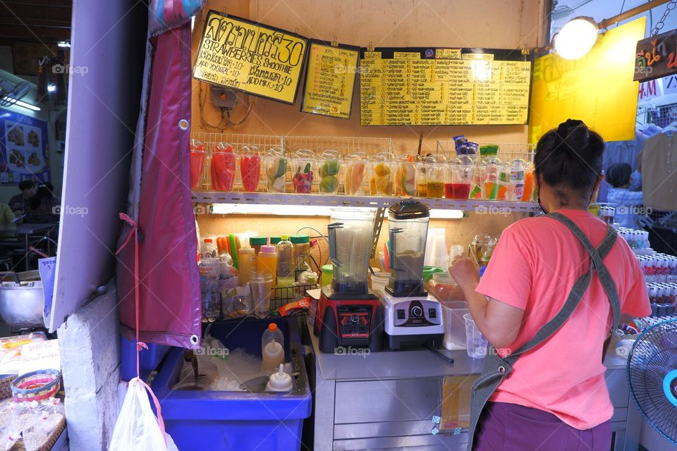 asian women open a fruit juice shop make fruit smoothies in front of the juice table