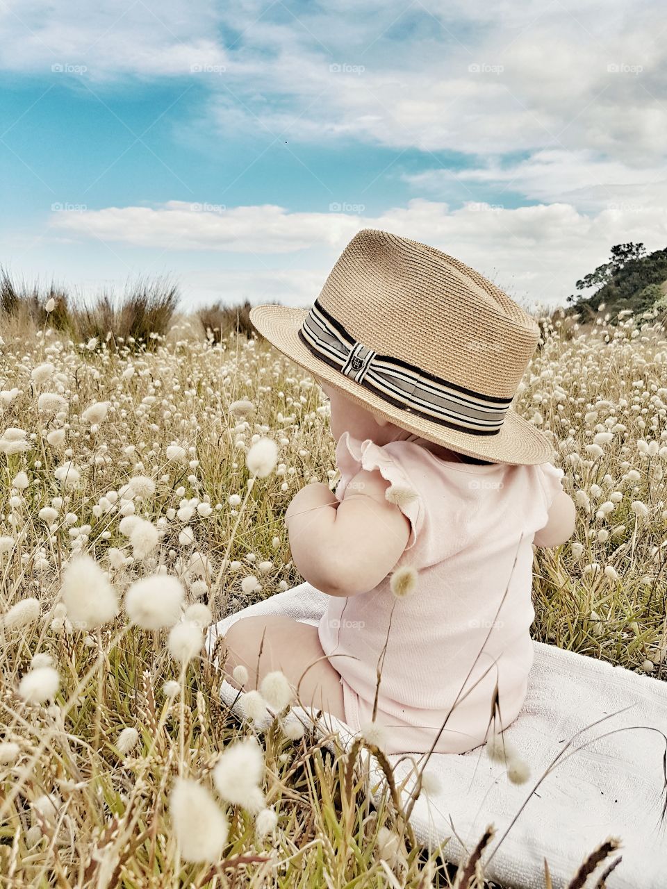 Baby Girl Playing in grass field with hat summer outdoors