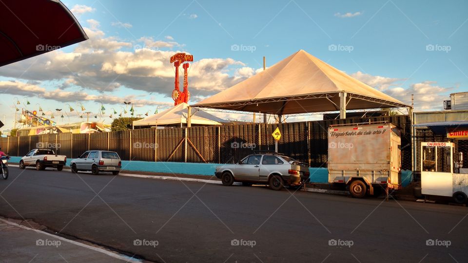 Tendas de eventos, parque de diversões carros, rua e céu.