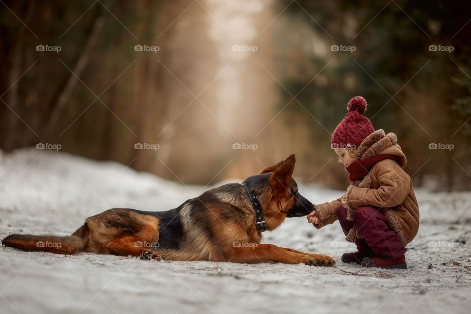 Little girl with German shepherd 6-th months puppy at early spring forest