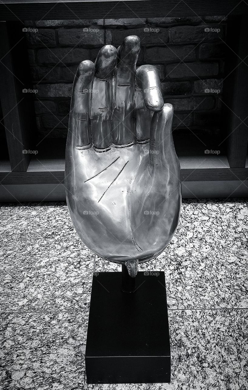 Decorative metal figurine in the form of a hand showing motivation gesture.  Black and white photo