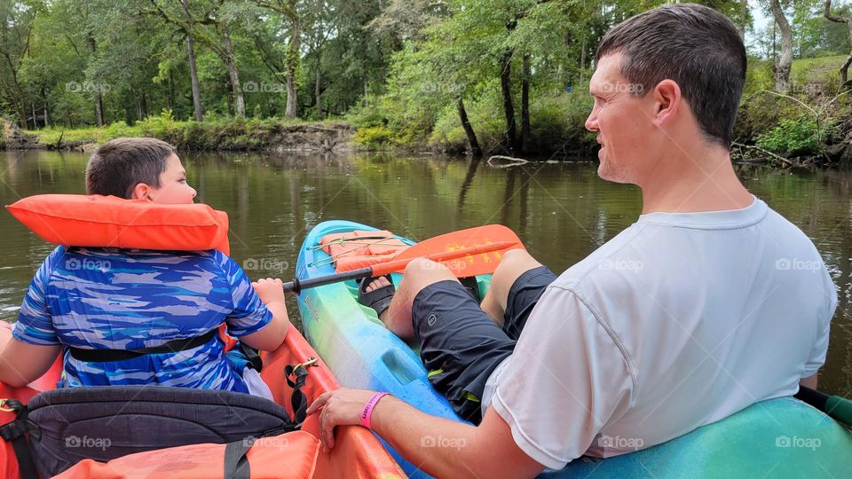 Father and son kayaking near a cold spring in Florida.