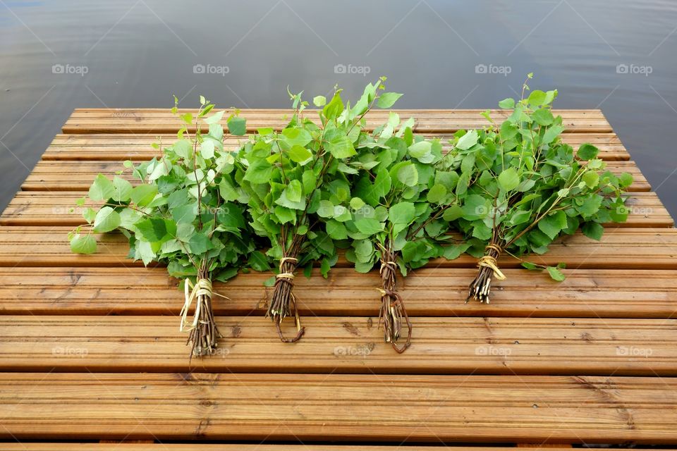 Traditional Finnish bath whisk. Traditional Finnish bath whisks made out of fresh birch leaves and twigs on a wet jetty by the lake on Midsummer Eve.