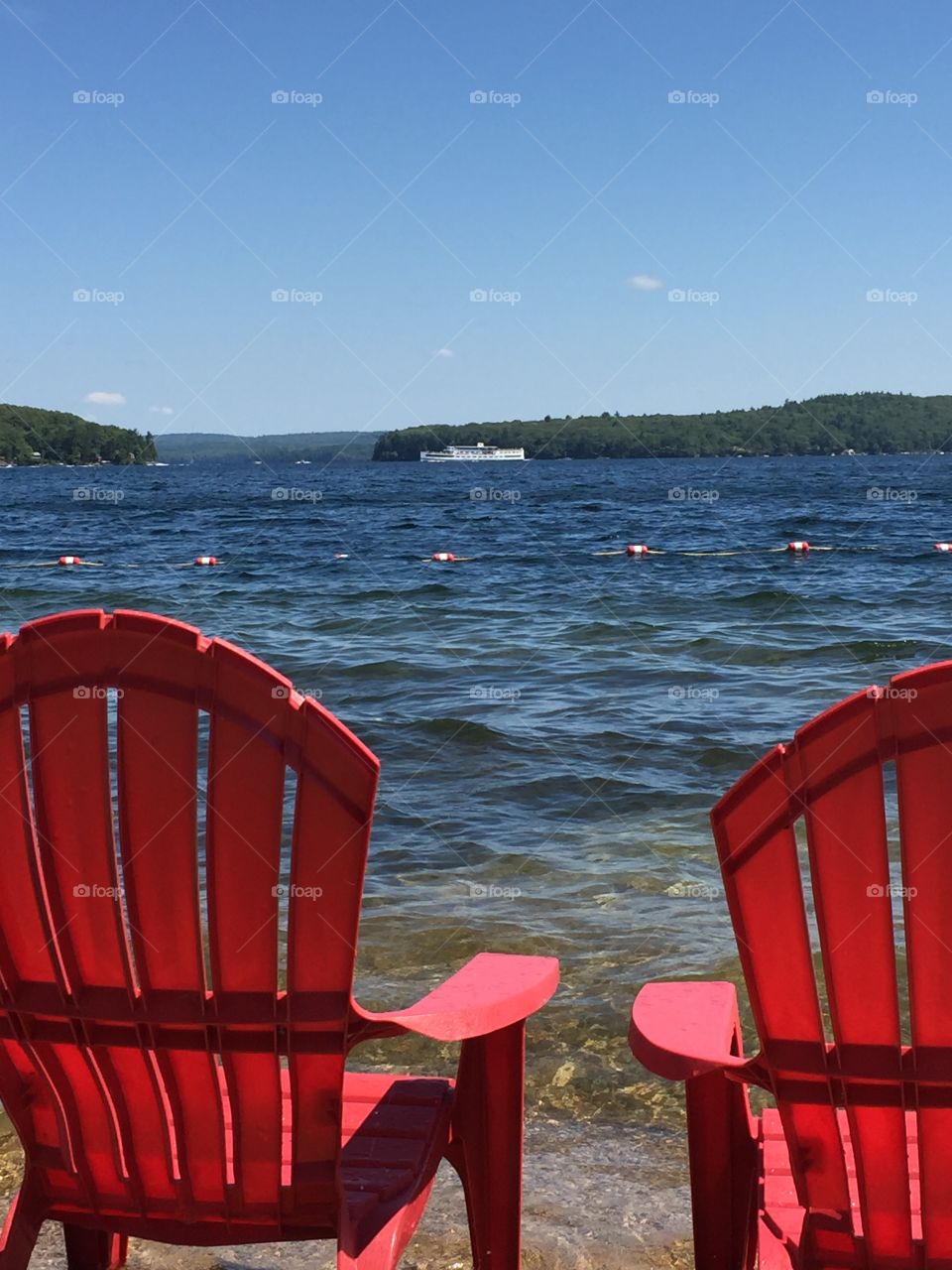 Two red chairs on beach in front of lake
