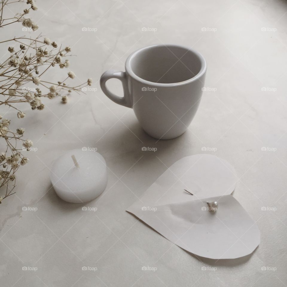 White on white. A cup of coffee, candle and a paper heart