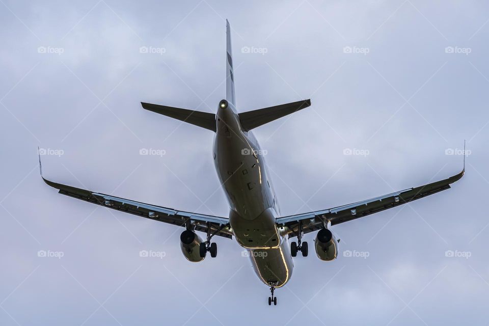 an airplane files through a cloudy sky with a red tail light
