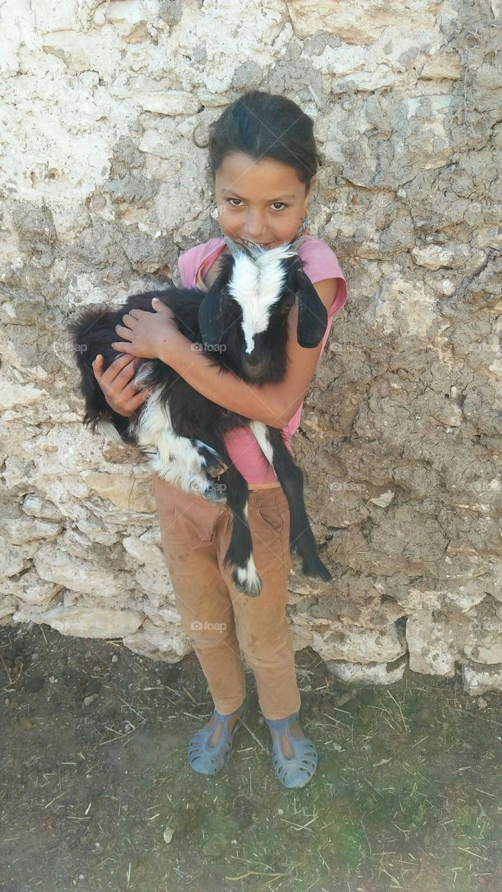 Beautiful girl holding  a charmant goat.