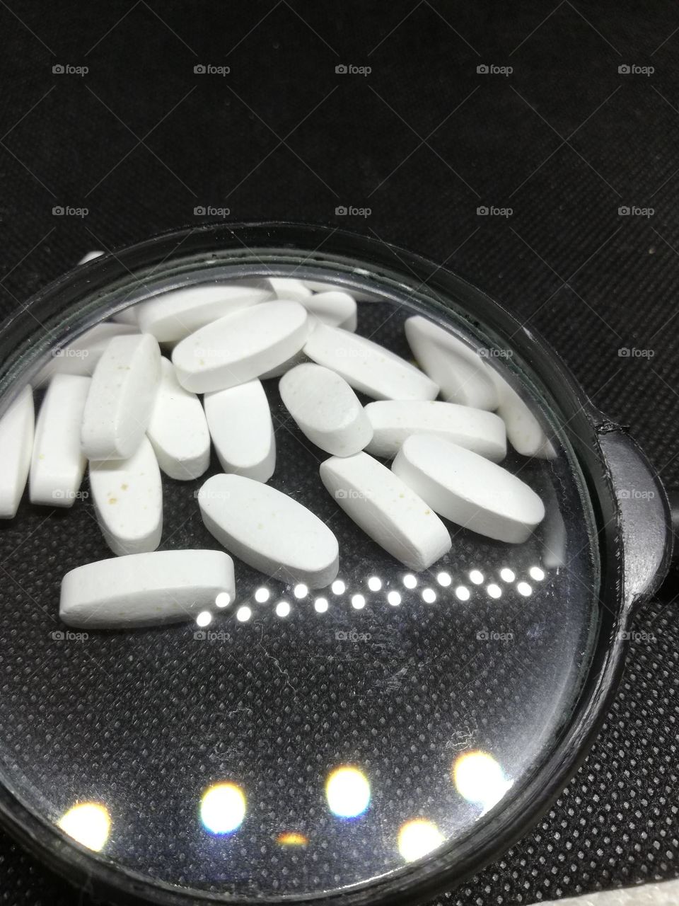 magnesium tablets On a black canvas under a magnifying glass