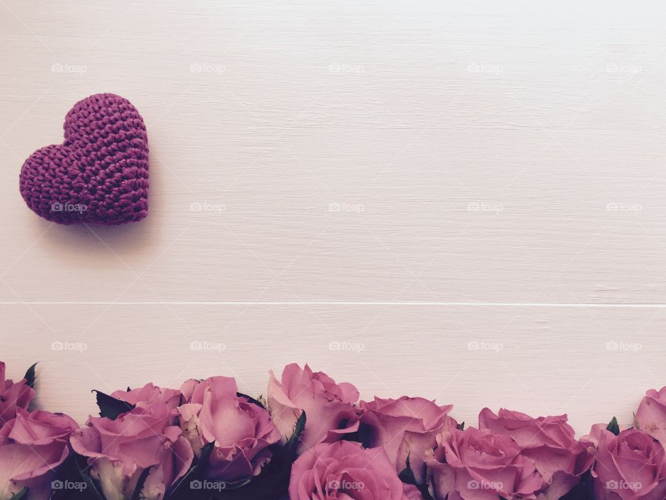 Vintage background with pink roses and pink knitted little heart, top view