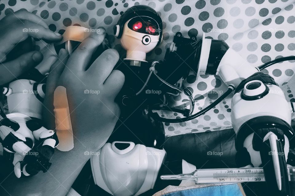 Child hands caring a sick robot.