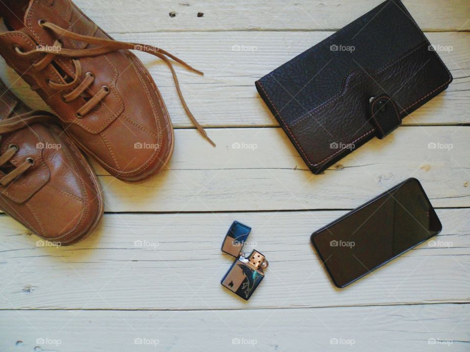 Brown leather men's shoes, notebook, cigarette lighter and smartphone