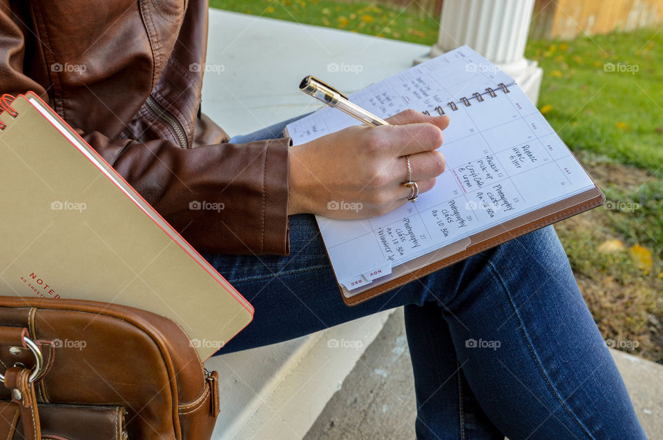 Woman writing in an At-a-Glance planner while sitting on concrete steps