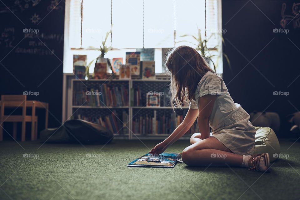 Child solving riddle in book in school library. Primary school pupil is involved in book with riddles. Smart girl learning to solve problems. Benefits of everyday practice. Child curiosity