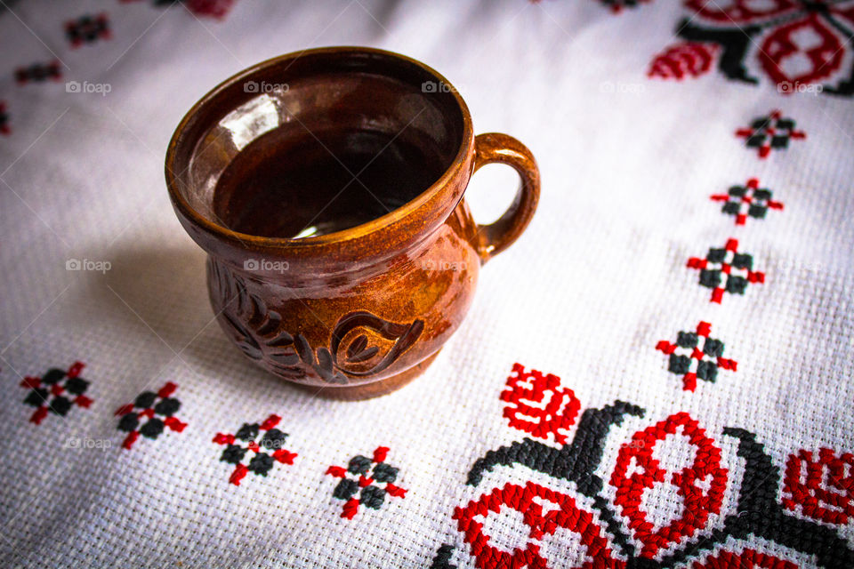 Beautiful traditional clay cup on a white traditional towel with red and black patterns stitching