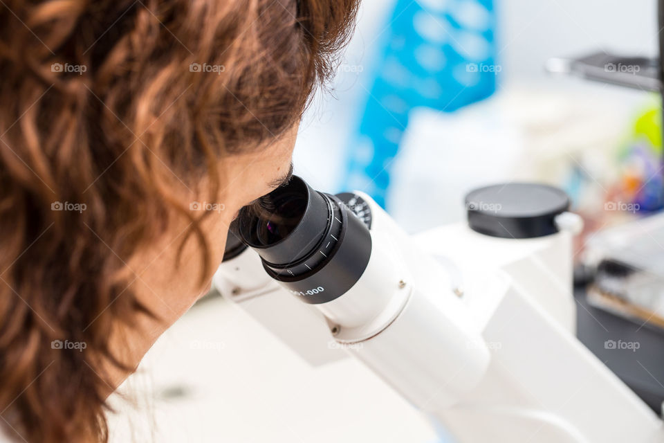 Scientist observing cells at microscope