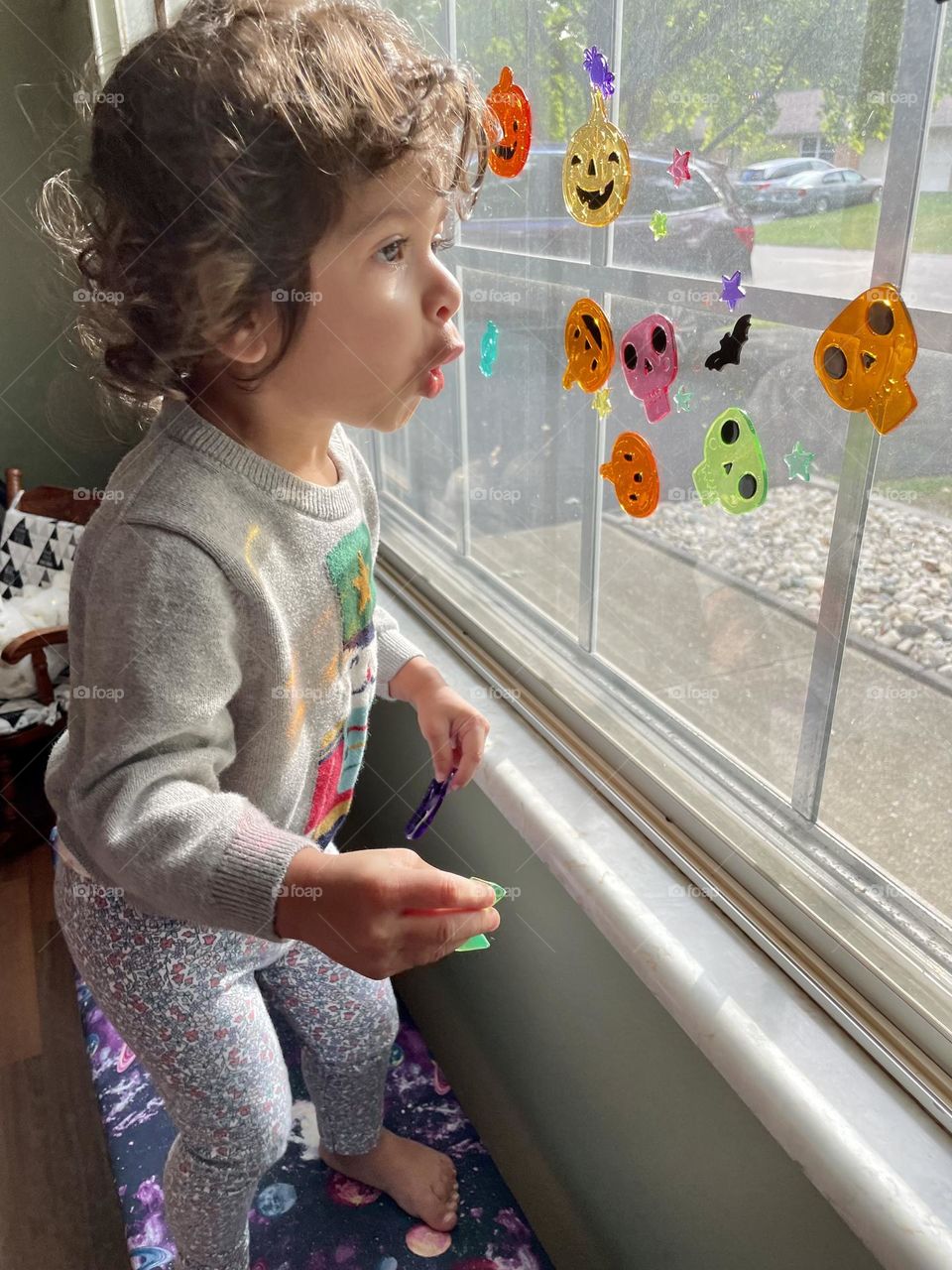 Toddler girl looking outside with a surprised look on her face, little girl is surprised by something outside window, little girl looking out window and showing emotion of surprise, facial expressions on a toddler, comical expression on a toddler