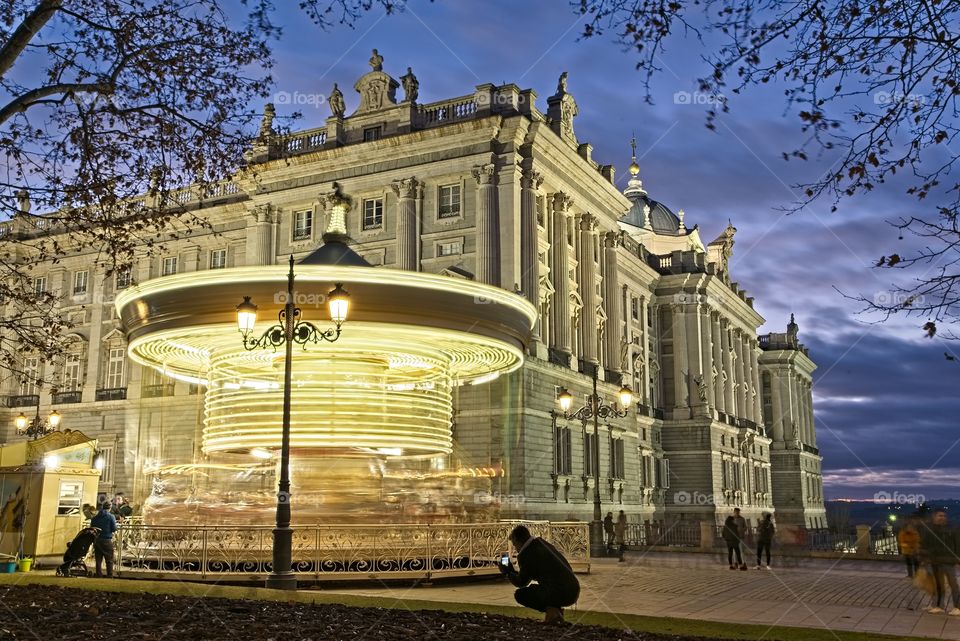 A carousel turns in front of the Royal Palace of Madrid at nightfall