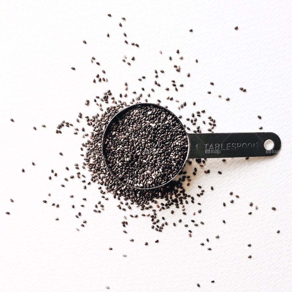 Chia seeds . 1 tablespoon of chia seeds on a white background