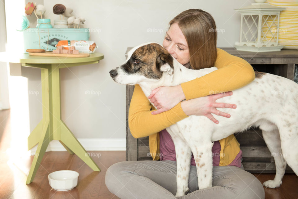 Young woman sitting on the floor and hugging her dog