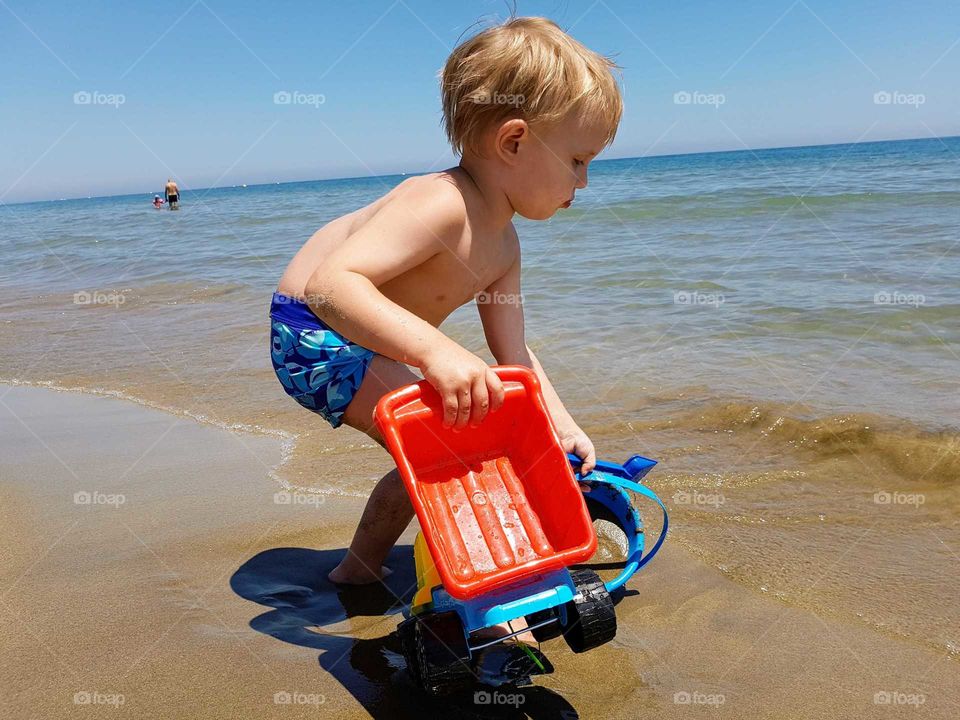 Boy with toy car on beach