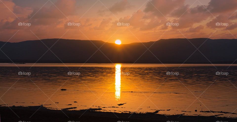 Shore of Dead Sea, sunrise over thr Jordanian mountains. Glowing path on the water.