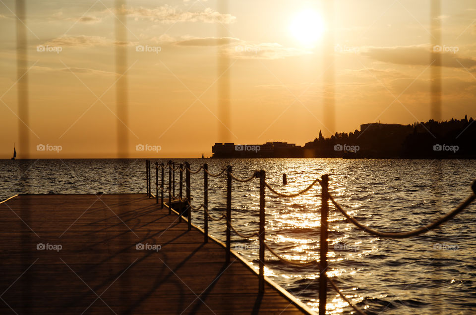 Seaside resort town in Slovenian coast against orange sunset sky in summer. Scenic view of the Adriatic sea in evening.