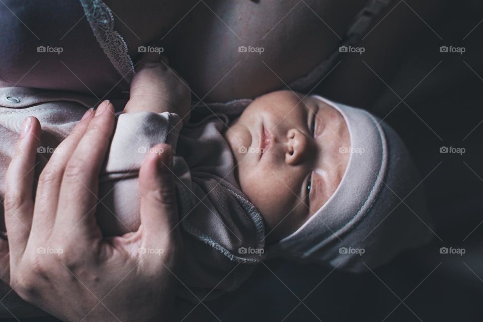 newborn baby sleeping in mother's arms