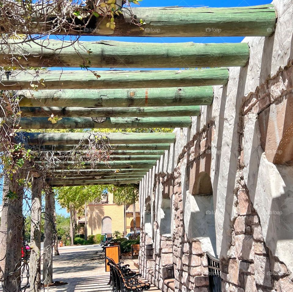 A walking canopy with benches at a town square 