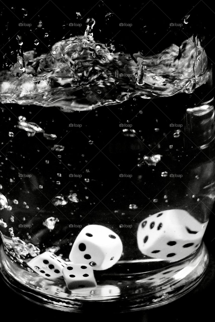 Water splash with White dice with black dots and black background 