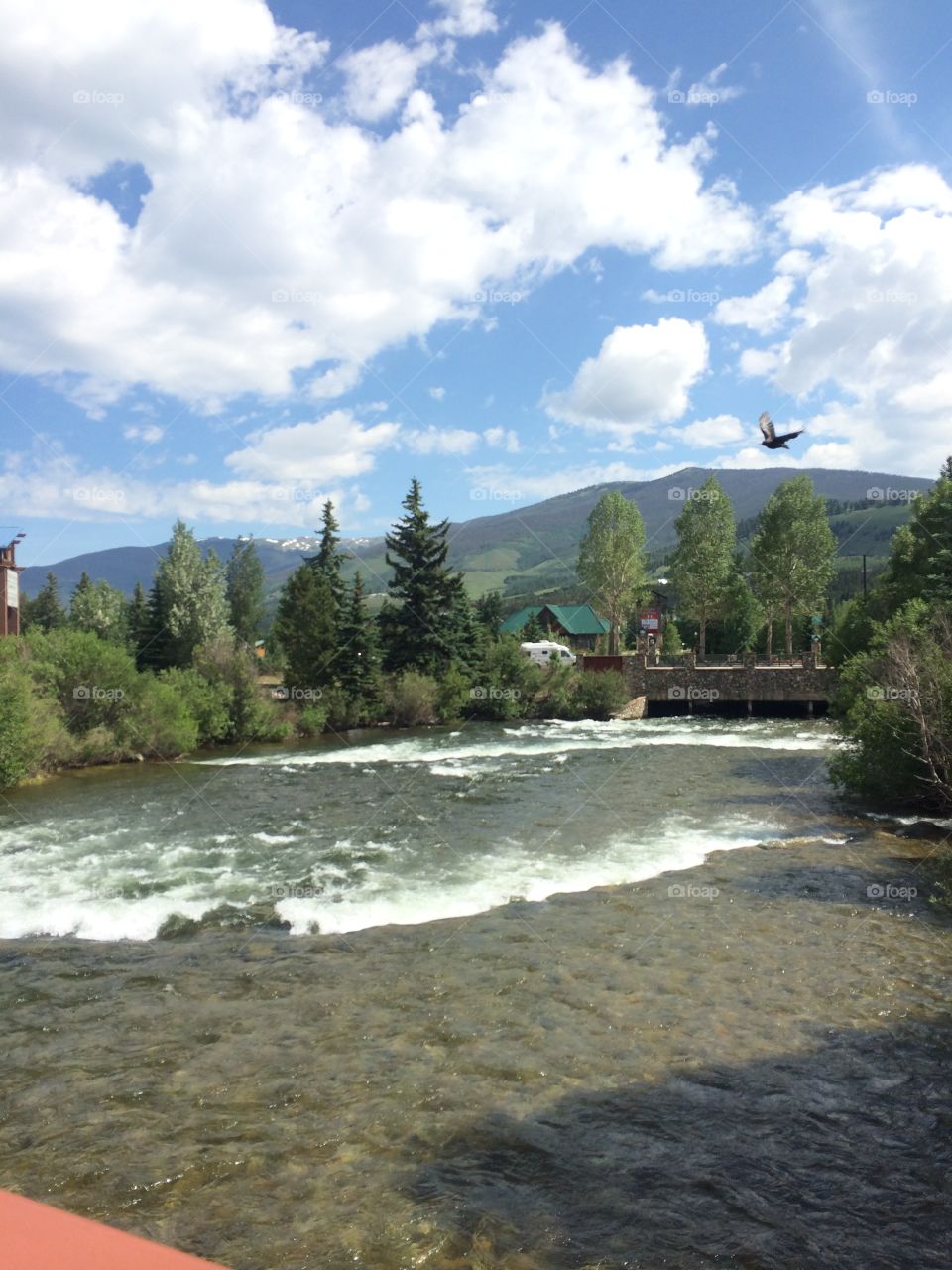 A photo of a light stream running under a bridge leading to an outlet mall in Breckinridge, Colorado on a sunny day. 
