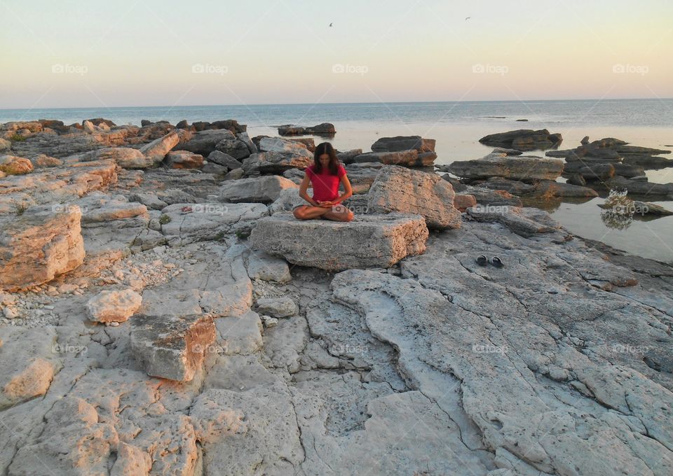 girl training yoga meditation on a sunset sea stone rock summer beautiful seascape
