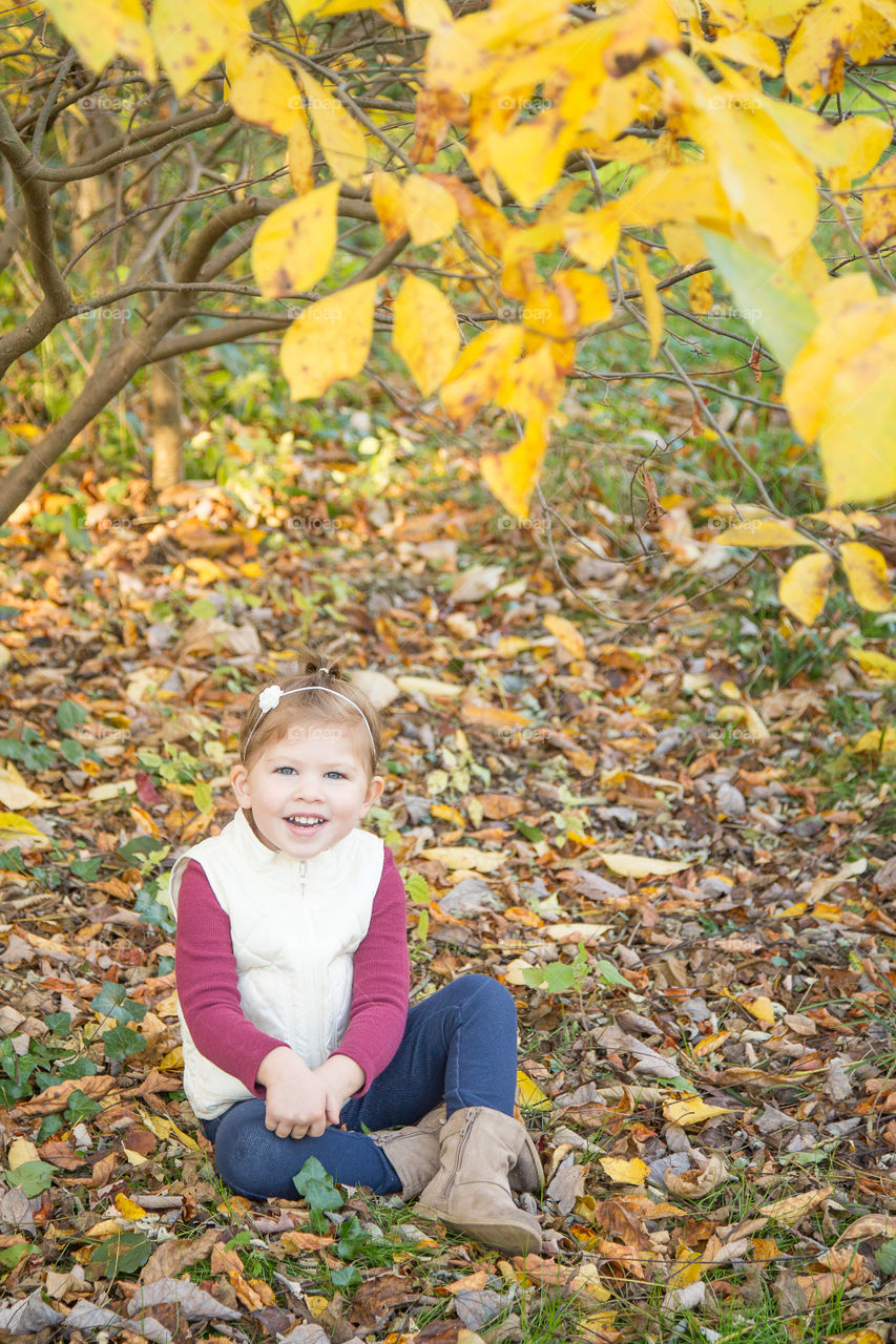 Happy girl sitting in autumn leaf