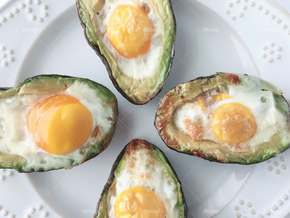 Breakfast Time Shots - flat lay closeup  of eggs baked in avocado halves on white plate