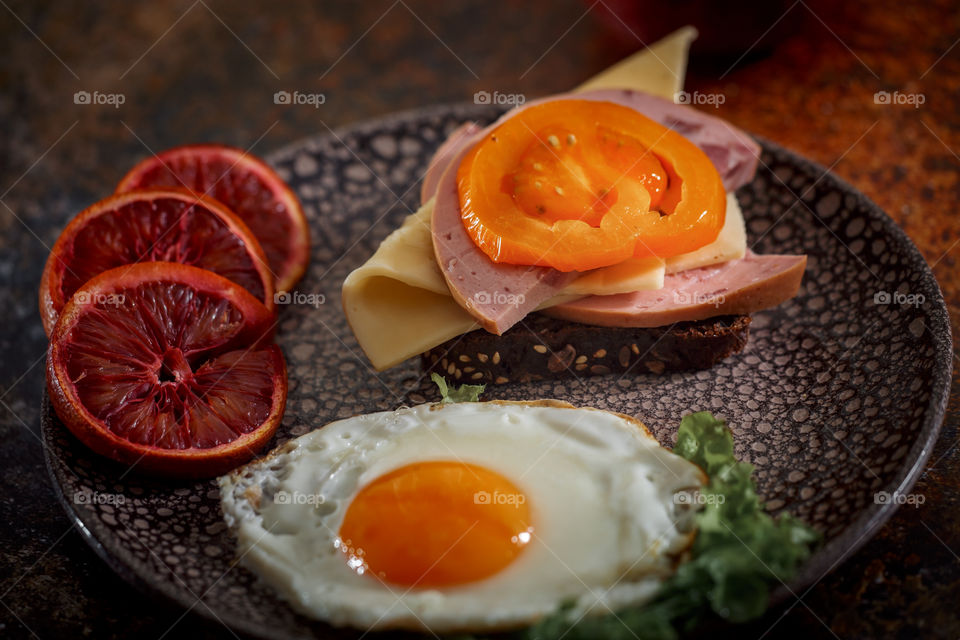 Sandwiches with fried egg orange tomato and red orange fruit 