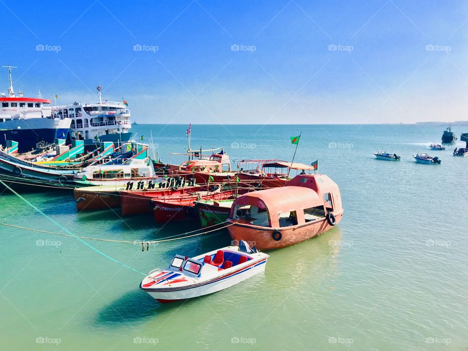 A small ferry with lots of Ships,boats, travel boats,speed boats etc for a large amount of travellers. Blue Sky with day light atmosphere a nice scenery. 