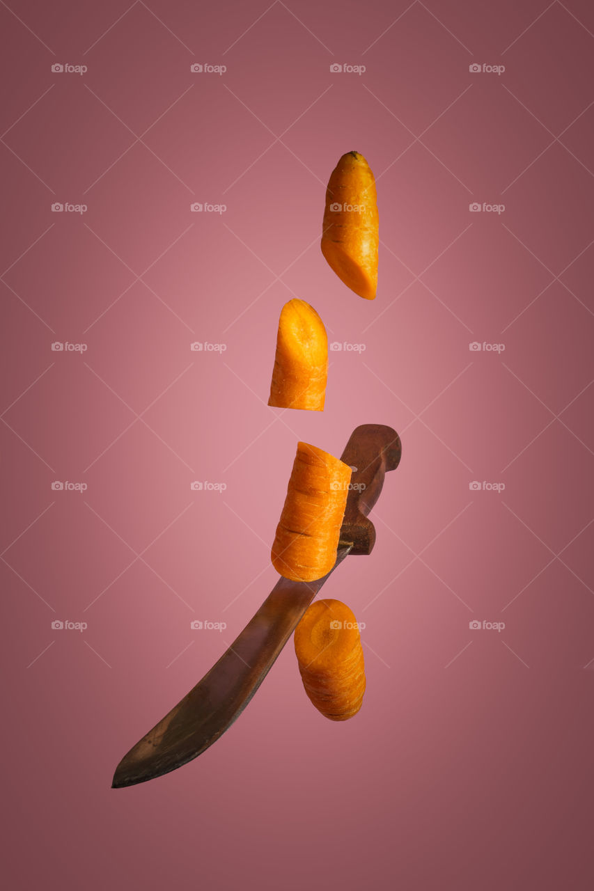 Floating knife slicing fresh carrot. Creative food concept