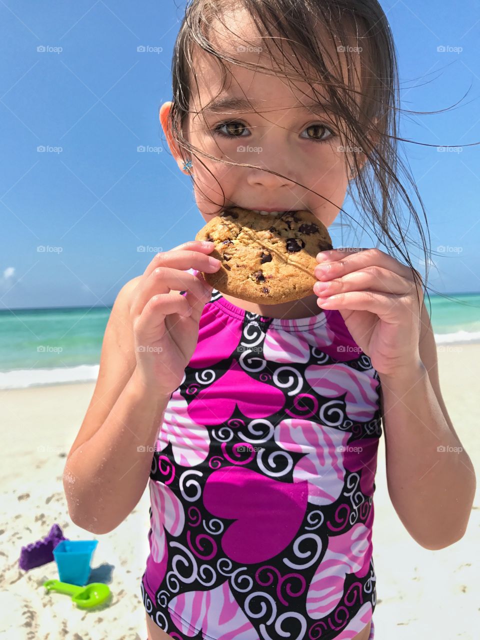 Close-up of a cute girl at beach eating cookie